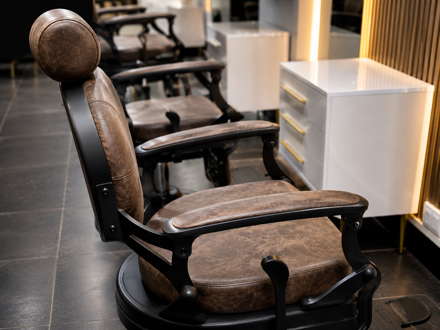 Hand-stitched leather barber chair on matte black flooring