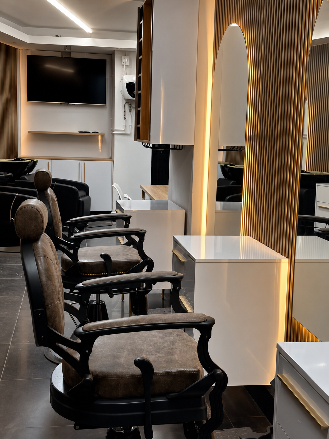Barber chairs beneath the arched mirror gallery — where every client is welcomed for their service